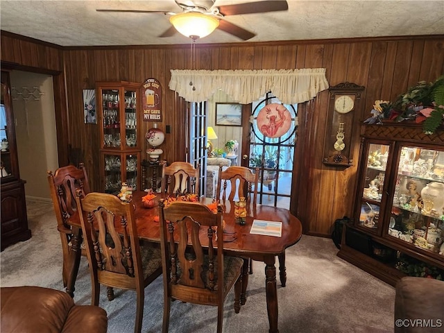 dining space with ceiling fan, wood walls, carpet, and crown molding