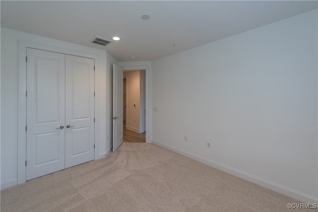 unfurnished bedroom featuring light colored carpet and a closet