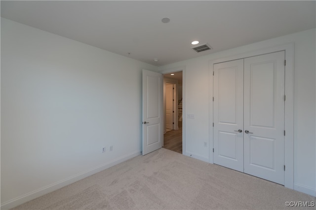 unfurnished bedroom featuring light carpet and a closet