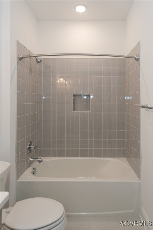 bathroom featuring tile patterned floors, tiled shower / bath, and toilet