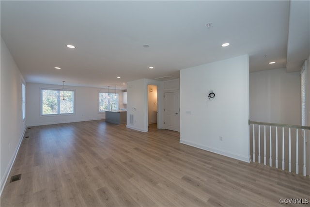 unfurnished living room with light hardwood / wood-style flooring and a notable chandelier