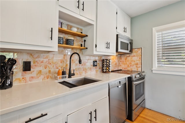 kitchen with light hardwood / wood-style floors, sink, white cabinetry, backsplash, and appliances with stainless steel finishes