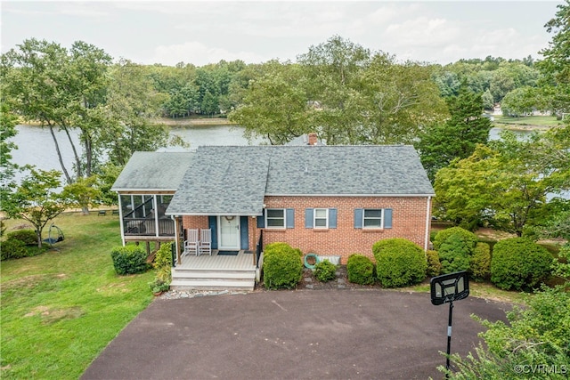 view of front facade with a water view, a front lawn, and a sunroom