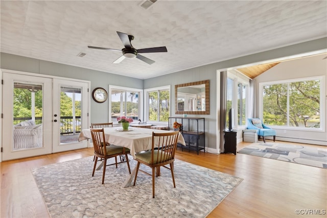 dining room featuring ceiling fan, light wood-type flooring, french doors, and vaulted ceiling