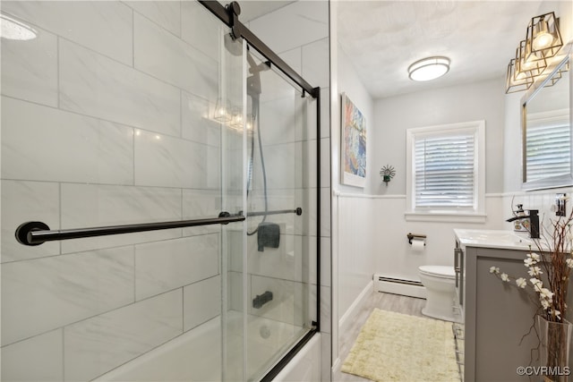 full bathroom featuring hardwood / wood-style flooring, a baseboard radiator, bath / shower combo with glass door, vanity, and toilet