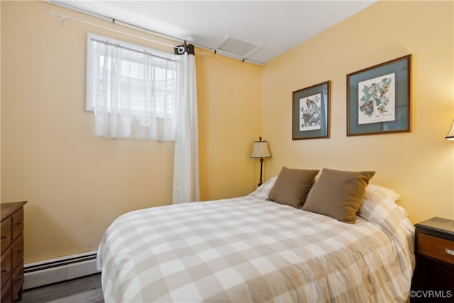 bedroom featuring a baseboard heating unit and hardwood / wood-style flooring