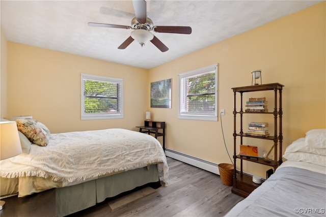 bedroom featuring a baseboard radiator, hardwood / wood-style floors, multiple windows, and ceiling fan