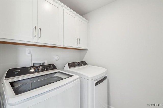 clothes washing area featuring washing machine and clothes dryer and cabinet space