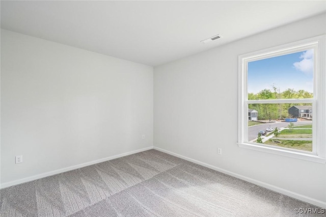 empty room featuring visible vents, carpet flooring, and baseboards