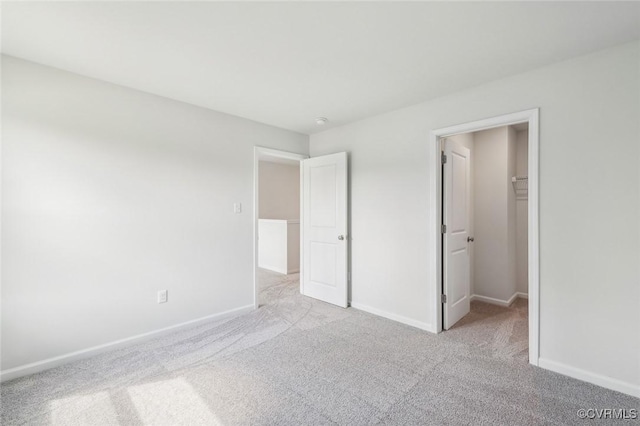unfurnished bedroom featuring baseboards, carpet flooring, and a walk in closet