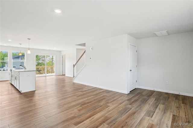 unfurnished living room featuring stairway, baseboards, recessed lighting, and light wood-type flooring