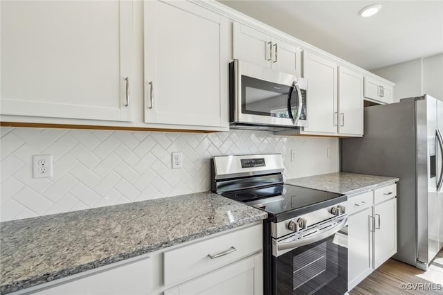 kitchen with white cabinets, light stone countertops, appliances with stainless steel finishes, and decorative backsplash