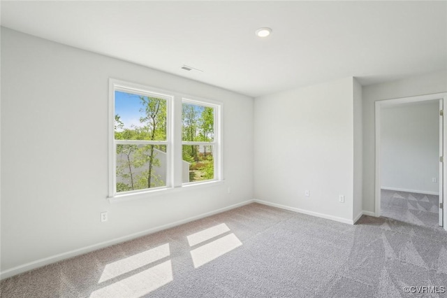 spare room with baseboards, visible vents, and carpet