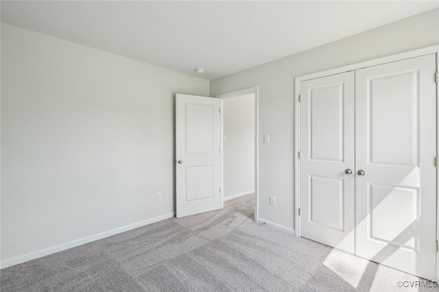 unfurnished bedroom featuring baseboards, carpet flooring, and a closet