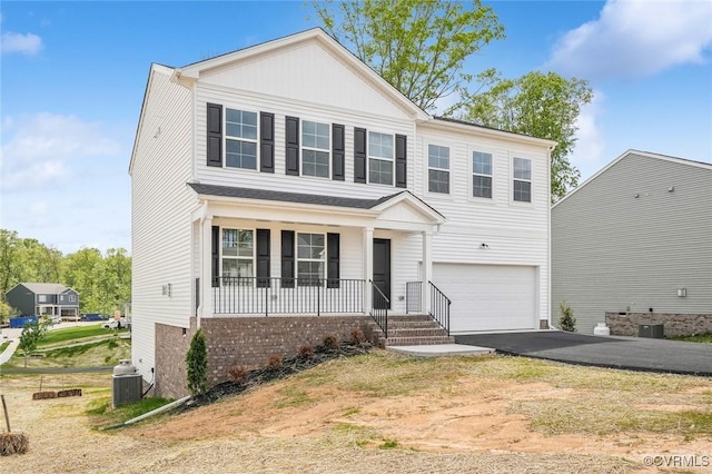 traditional-style home with a garage, central AC, covered porch, and aphalt driveway
