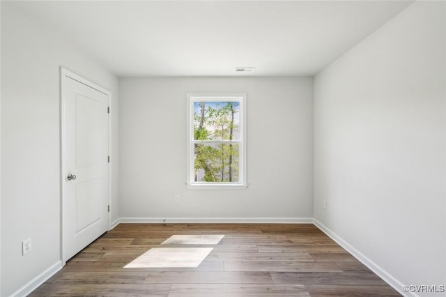 spare room with baseboards and wood finished floors