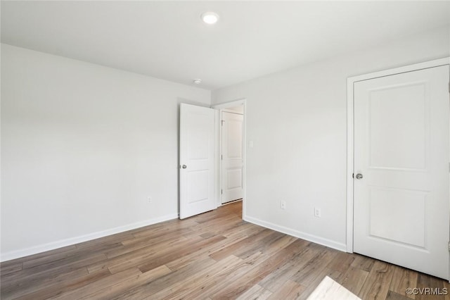 unfurnished bedroom featuring recessed lighting, light wood-style floors, and baseboards