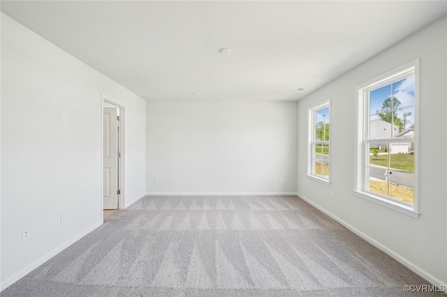 spare room with light colored carpet and baseboards