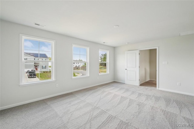 empty room featuring baseboards, visible vents, and carpet