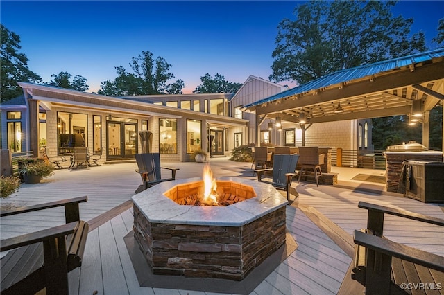 deck at dusk featuring a gazebo and an outdoor fire pit