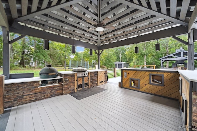 wooden deck featuring an outdoor bar, ceiling fan, a gazebo, and exterior kitchen