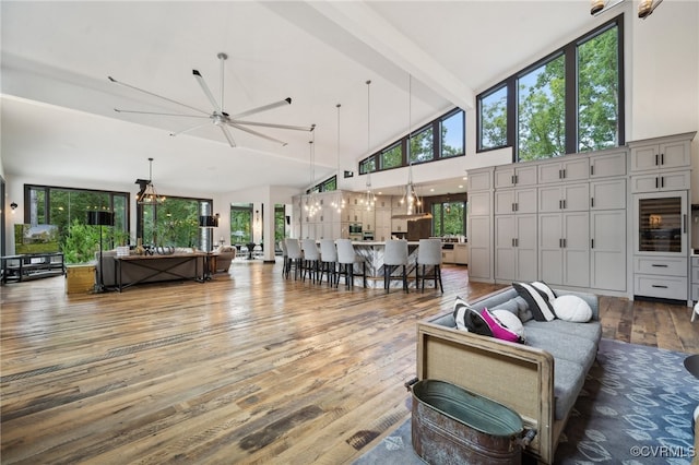 living room featuring hardwood / wood-style flooring, ceiling fan, high vaulted ceiling, and beam ceiling