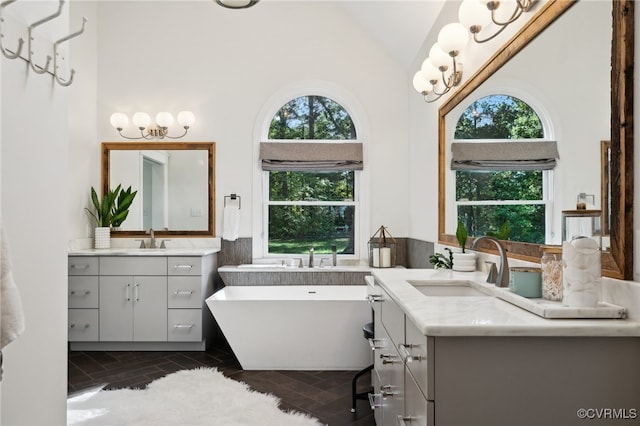 bathroom featuring a tub to relax in, vanity, high vaulted ceiling, and a healthy amount of sunlight