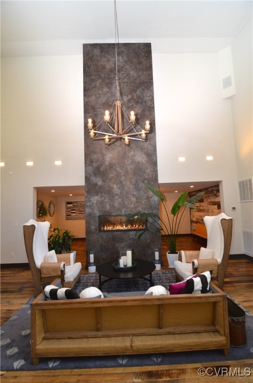 living room with dark wood-type flooring, a large fireplace, and a high ceiling