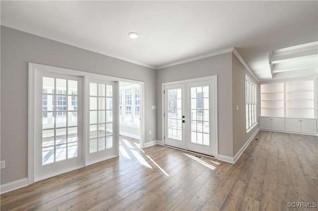 doorway to outside with a wealth of natural light, built in features, french doors, and light wood-type flooring