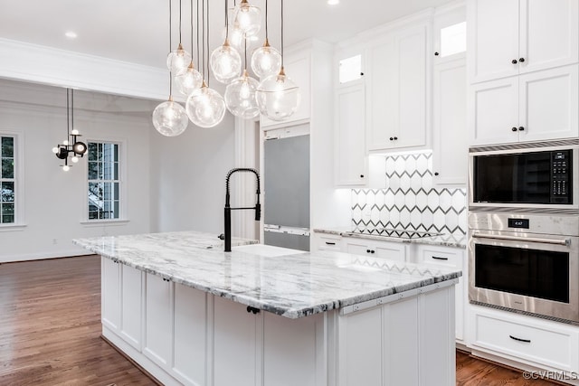 kitchen with a center island with sink, stainless steel appliances, dark hardwood / wood-style flooring, and white cabinetry