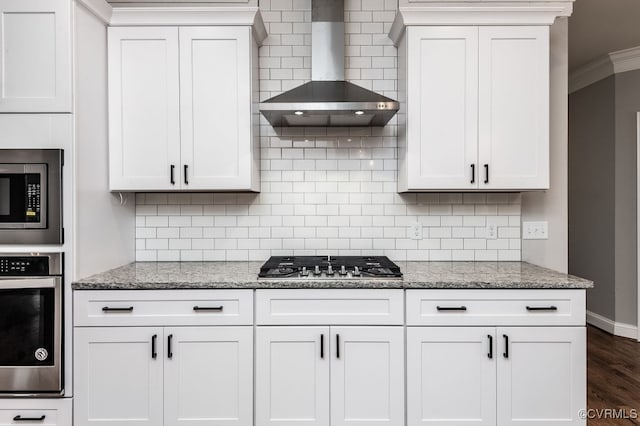 kitchen with light stone counters, dark wood-type flooring, wall chimney range hood, stainless steel appliances, and crown molding