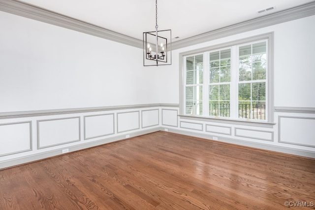 unfurnished dining area featuring ornamental molding, hardwood / wood-style floors, and a notable chandelier