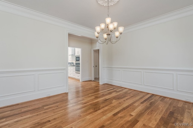 unfurnished dining area with wood-type flooring, crown molding, and a chandelier