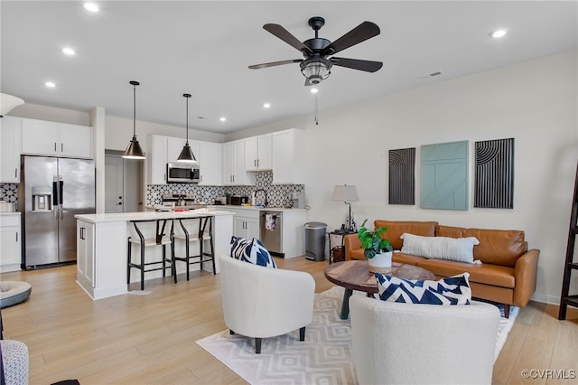 living room with light hardwood / wood-style floors, ceiling fan, and sink