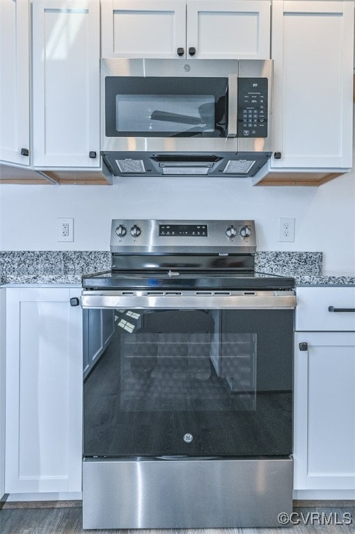 kitchen with stainless steel appliances, white cabinetry, and light stone counters