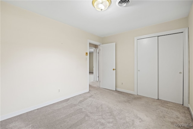 unfurnished bedroom featuring light carpet and a closet