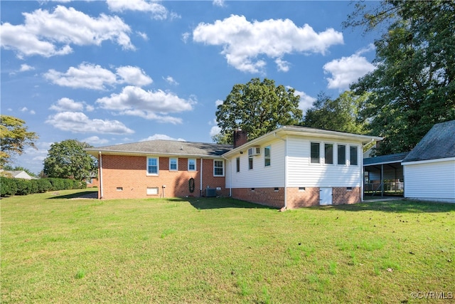 rear view of property with central AC unit and a lawn