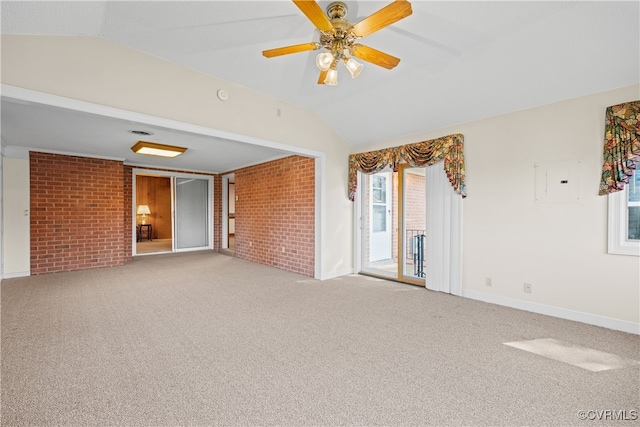 empty room with brick wall, vaulted ceiling, carpet flooring, and ceiling fan