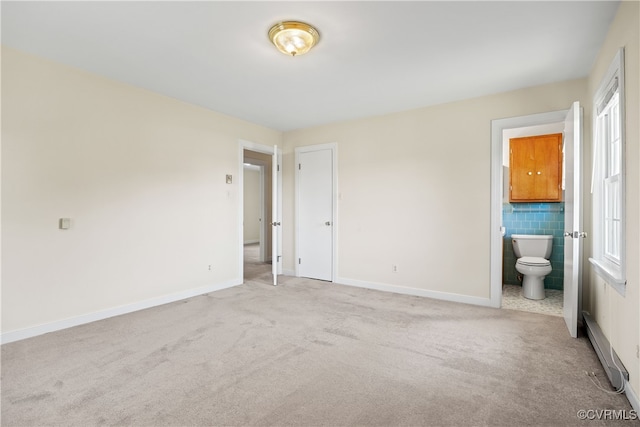 unfurnished bedroom featuring light colored carpet and ensuite bathroom