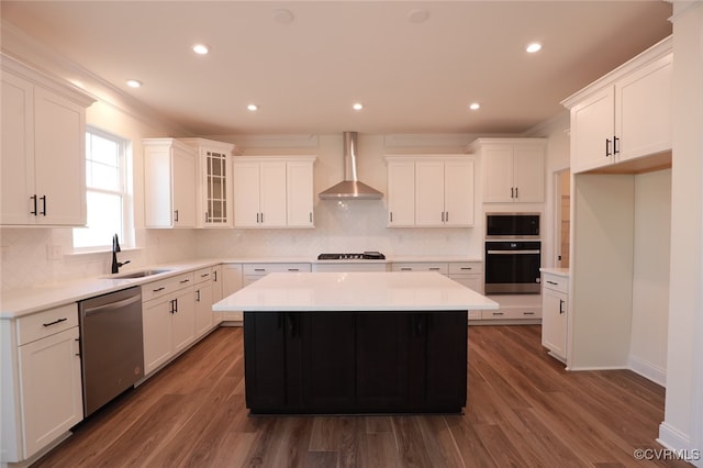 kitchen featuring appliances with stainless steel finishes, a kitchen island, dark hardwood / wood-style flooring, sink, and wall chimney range hood