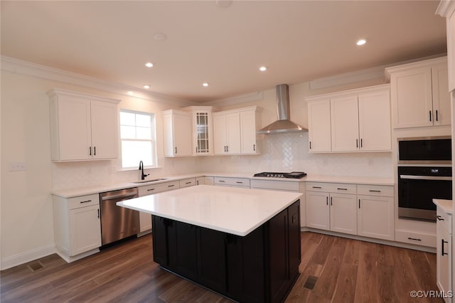 kitchen featuring sink, wall chimney range hood, appliances with stainless steel finishes, a center island, and dark hardwood / wood-style flooring