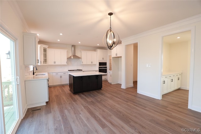 kitchen featuring wall chimney exhaust hood, white cabinetry, a center island, and a wealth of natural light