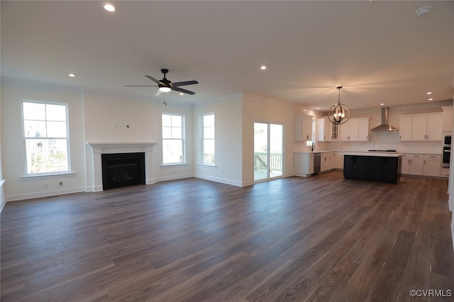 unfurnished living room with ceiling fan with notable chandelier, ornamental molding, dark hardwood / wood-style floors, and sink