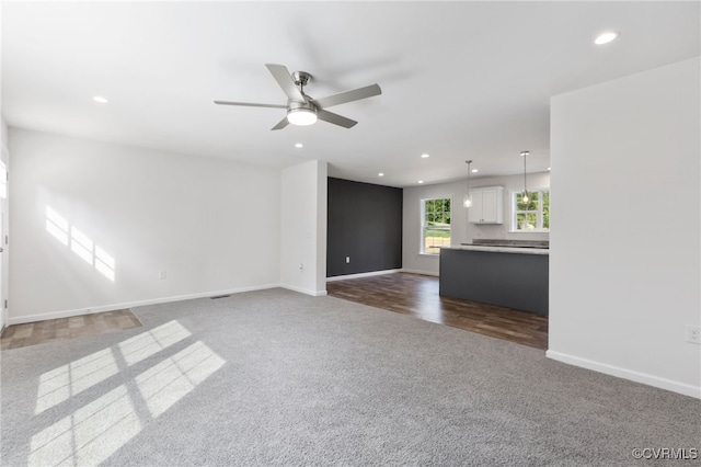 unfurnished living room featuring ceiling fan and dark hardwood / wood-style floors