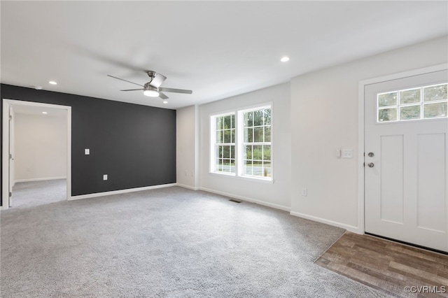 foyer featuring ceiling fan and light colored carpet