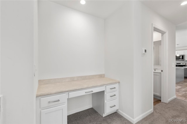 unfurnished office featuring light colored carpet and built in desk