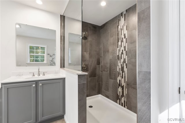 bathroom with a tile shower and vanity