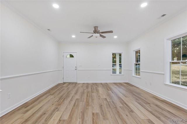 unfurnished room with light wood-type flooring, ornamental molding, and a wealth of natural light