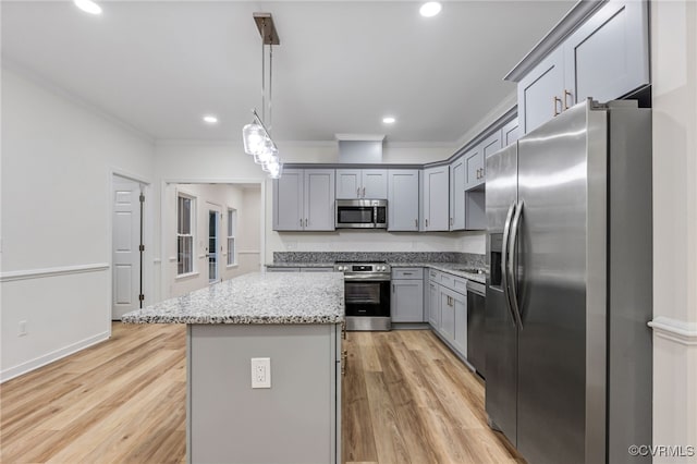 kitchen with light stone counters, pendant lighting, stainless steel appliances, a center island, and light hardwood / wood-style flooring