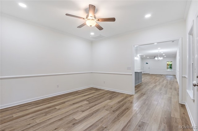 spare room with ornamental molding, ceiling fan with notable chandelier, and light hardwood / wood-style floors